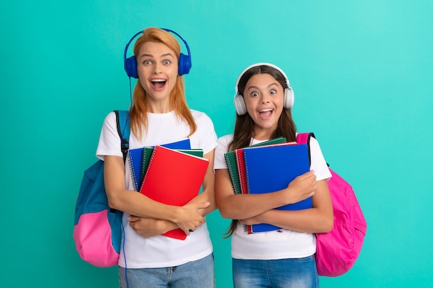 Foto ritorno a scuola l'educazione online per l'infanzia ha sorpreso l'allievo e lo studente mamma e ragazza adolescente in cuffie l'insegnante privato e il bambino portano lo zaino la famiglia aiuta la madre e la figlia a tenere il taccuino