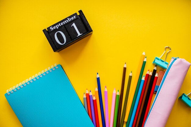 Back to school colorful flat lay. Pencils notepad alarm clock clips and pen holder. 