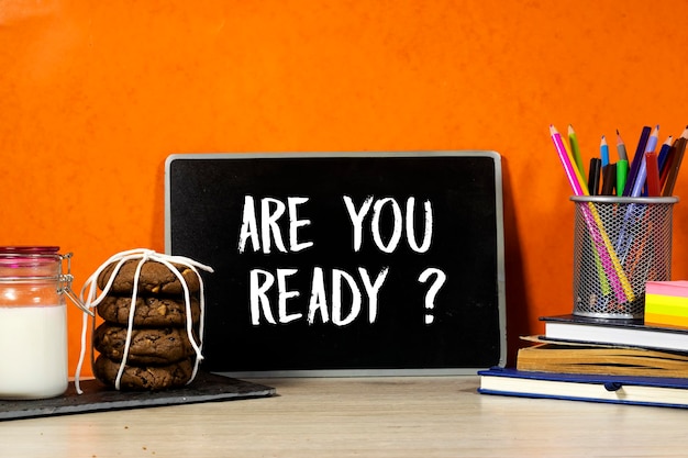 Back to school concept are you ready question on blackboard with pencilbox and books notebook