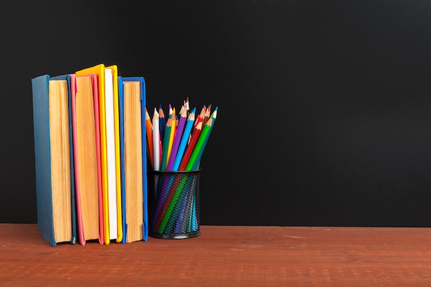 Back to school concept background. Blackboard with books and apple on wooden desk 