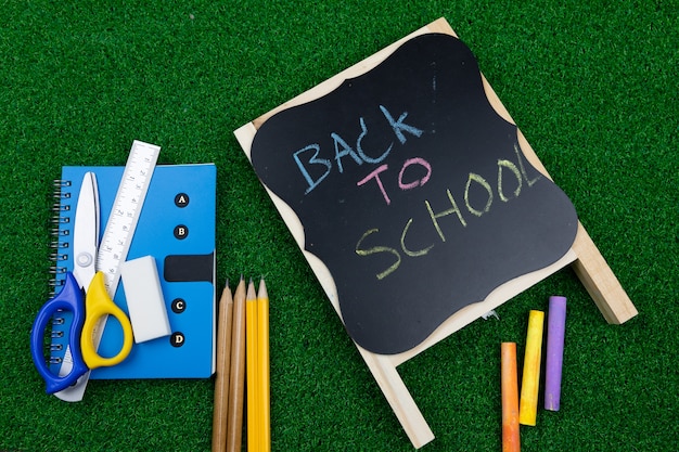 Back to school concept book, chalk color, pencil, ruler, eraser put on green lawn