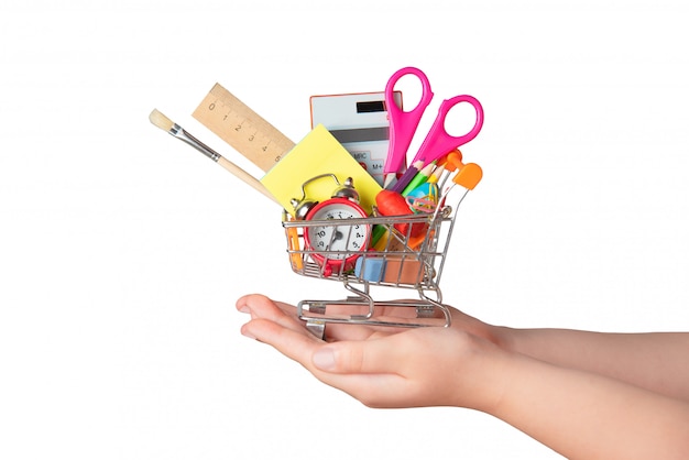 Back to school concept. Bright stationery items in a mini supermarket trolley in hand isolated on white