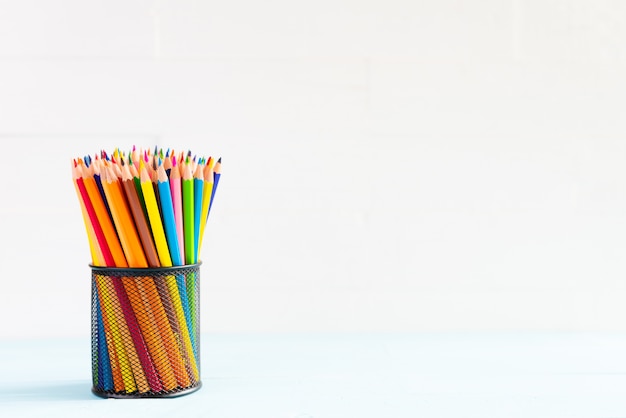 Back to school Concept. Colorful pencils in box on white wooden background.