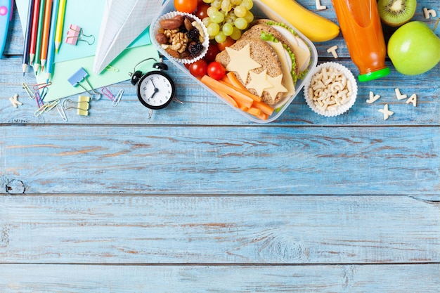 Photo back to school concept healthy lunch box and colorful stationery on turquoise wooden table top view