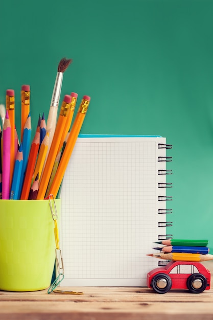 Back to school concept. Miniature Red Car Carrying a colorful pencils and red apple on wooden table