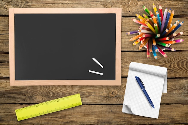 Foto torna al concetto di scuola. matite, penna, blocco note e lavagna