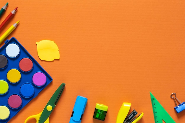 Back to school concept. School and office supplies on the office table. Orange background.Flat lay with copy space.Autumn