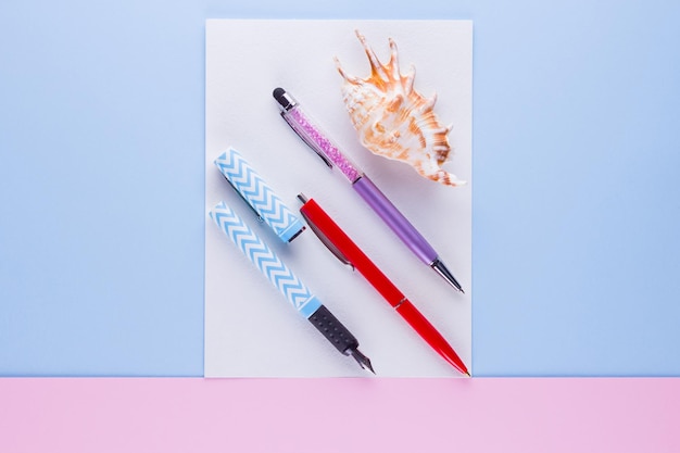 Photo back to school concept school stationery and seashell on pink blue background multicolored pens