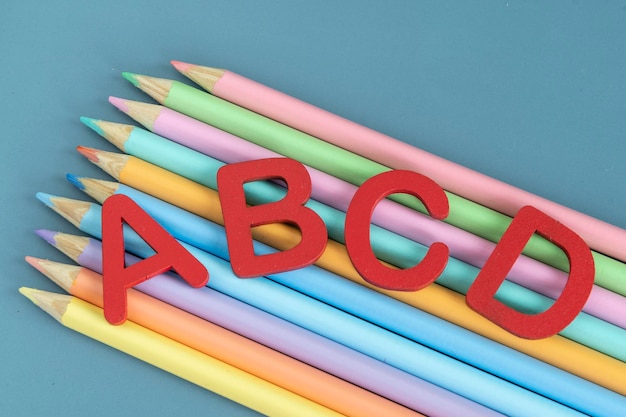 Foto concetto di ritorno a scuola con lettere assortite e matite colorate in colori pastello