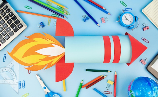 Back to school Concept with paper rocket and school supplies on a blue background Education concept