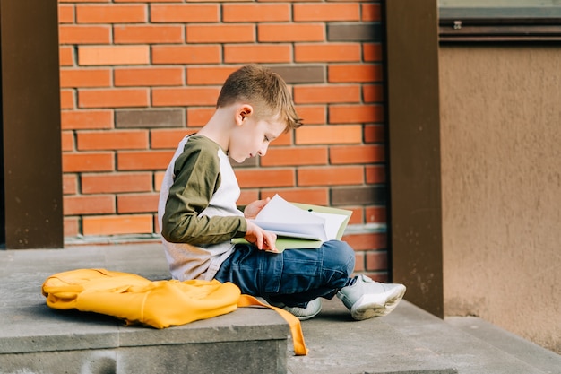 Back to school cute child with backpack holding notepad and training books going to school boy pupil