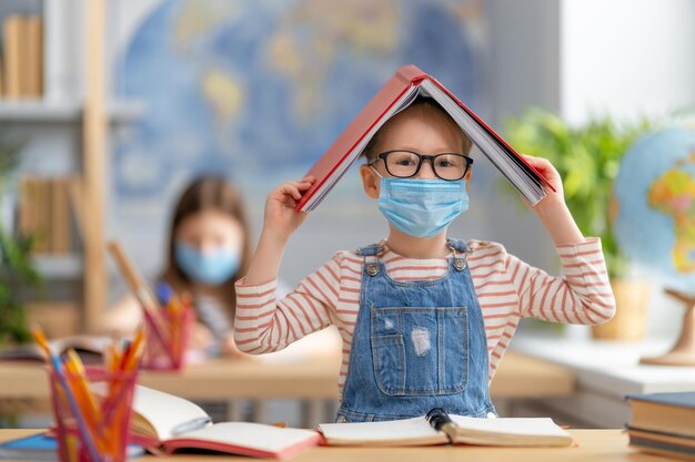 Back to school Cute industrious children are sitting at  desks indoors