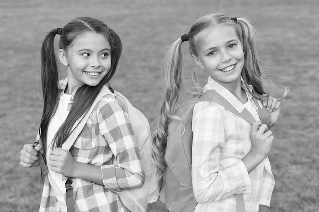 Back to school Cute schoolgirls with long ponytails Ending of school year Cheerful smart schoolgirls Happy schoolgirls outdoors Small schoolgirls with backpacks September Vacation is over