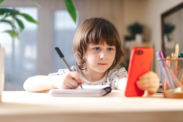 Photo back to school distance learning online education kid boy studying at home with mobile cell phone