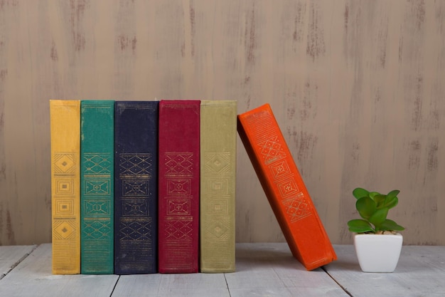 Back to school and education concept - heap colorful hardback books on white wooden table on brown background