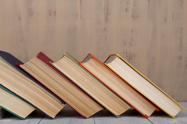 Back to school and education concept - heap colorful hardback books on white wooden table on brown background