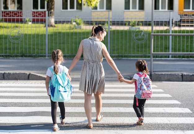 Back to school education concept with girl kids, elementary students, carrying backpacks going to class