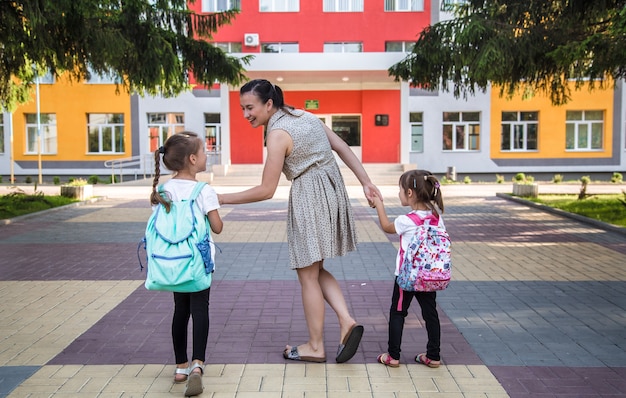 Back to school education concept with girl kids, elementary students, carrying backpacks going to class