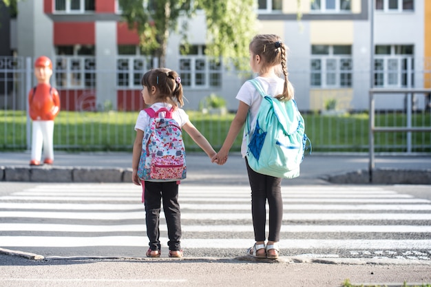 Back to school education  with girl kids, elementary students, carrying backpacks going to class