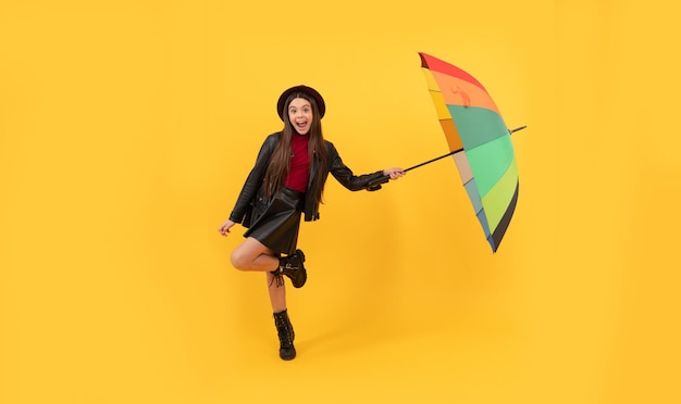 Back to school. fall fashion accessory. happy stylish girl in leather wear. cheerful teen child hold colorful parasol. kid in hat with rainbow umbrella. autumn season. rainy weather forecast.