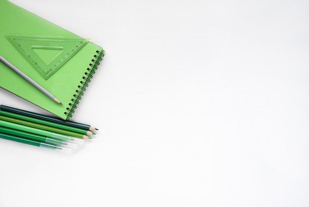 Back to school. Flat lay green notebook, pencil on a white background with copy space. Banner background