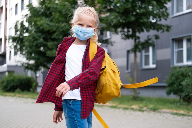 Back to school Girl wearing mask and backpacks protect and safety from coronavirus Child going school after pandemic over Looking at camera students are ready for new school year