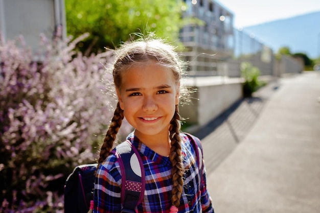 Photo back to school girl with backpack goes to school at the first day after vacation