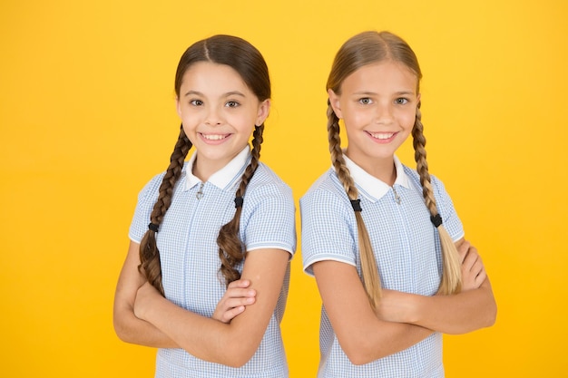 Back to school. happy beauty with pigtails. happy childhood. brunette and blond hair. sisterhood concept. best friends. vintage style. small girls in retro uniform. old school fashion. fashion model.
