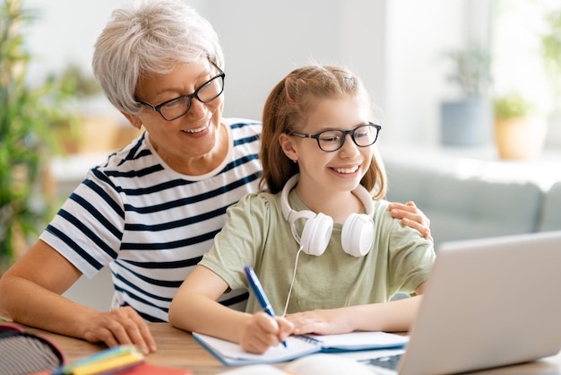 Back to school. Happy child and adult are sitting at desk. Girl doing homework or online education.