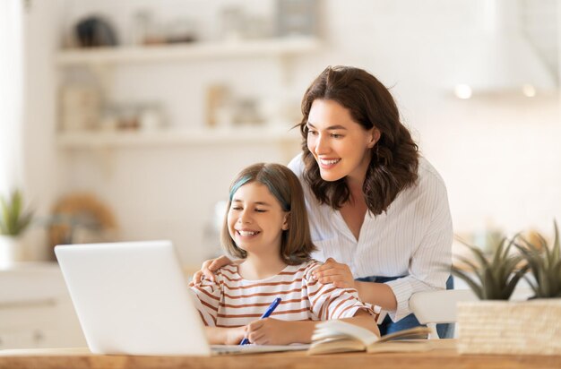 Back to school. Happy child and adult are sitting at desk. Girl doing homework or online education.