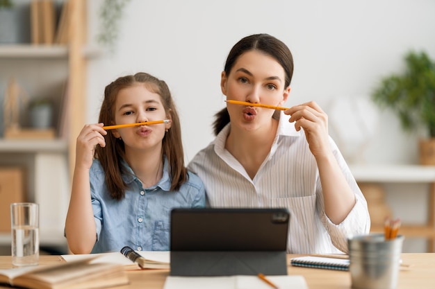 Back to school. Happy child and adult are sitting at desk. Girl doing homework or online education.