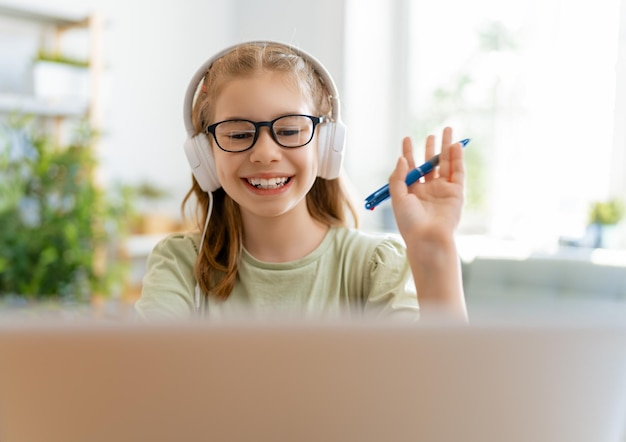 Back to school. Happy child is sitting at desk. Girl doing homework or online education.