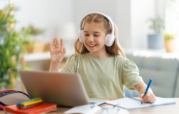 学校に戻る。幸せな子供は机に座っています。宿題やオンライン教育をしている女の子。