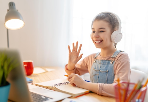 Back to school. Happy child is sitting at desk. Girl doing homework or online education.