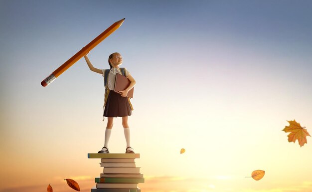 Photo back to school happy cute industrious child standing on the tower of books