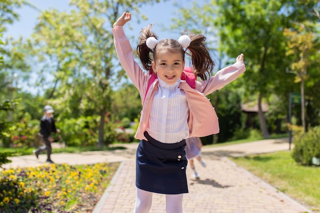 학교로 돌아가기 행복한 웃는 아이가 초등학교에 가다 야외에서 학교 가방을 든 아이