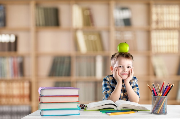 Back to school and happy time! Cute industrious child is sitting at a desk indoors.