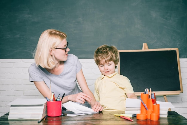 Back to school and happy time Teacher helping young boy with lesson Blackboard background copy space Preschooler