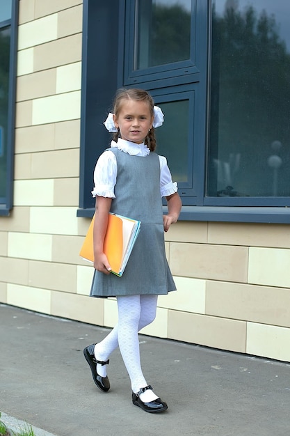 Photo back to school a hardworking child with a book the concept of education time to work hard a smart little student september 1 a schoolgirl with a folder in the school yard