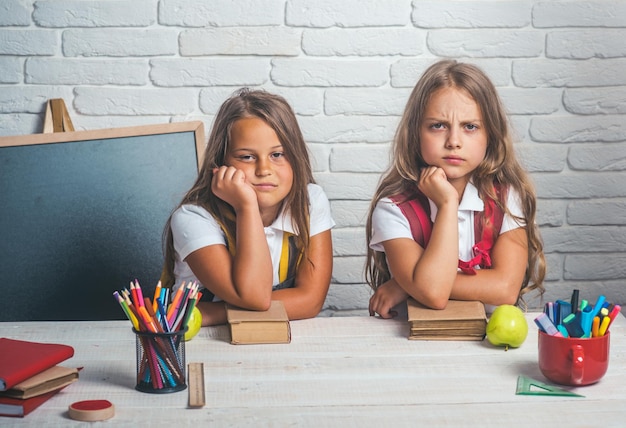 Ritorno a scuola e scuola a casa. scolari annoiati alla lezione del 1 settembre. tempo scolastico delle ragazze. amicizia delle sorelline in classe al giorno della conoscenza. le bambine mangiano la mela durante la pausa pranzo.