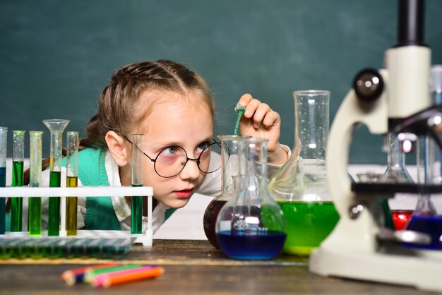 Ritorno a scuola e scuola a casa. la scienza e il concetto di educazione. piccolo scienziato felice che fa esperimento con la provetta. ritratto da vicino.