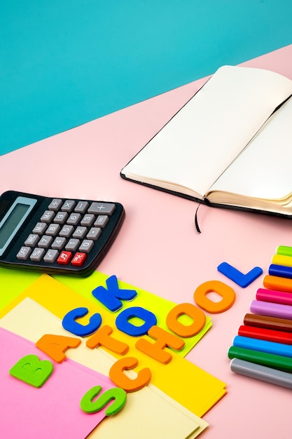 Back to school letters, with school supplies on top of a pink table.