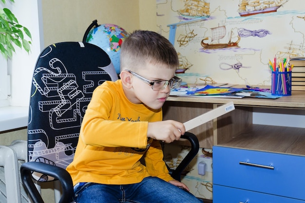 Photo back to school. little boy doing homework at home. backpack full of books, pencils. online education