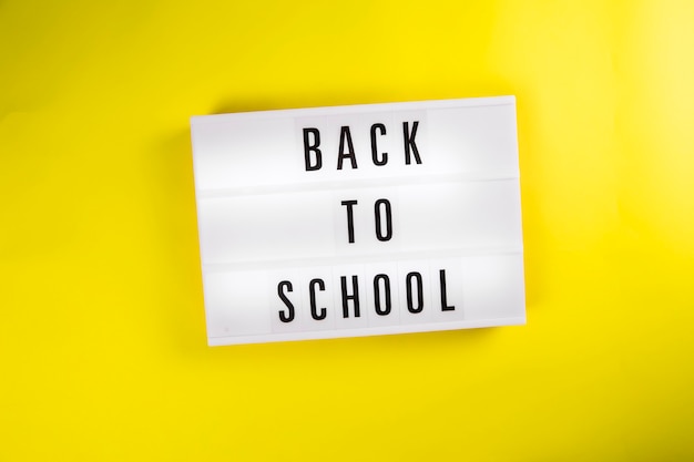 Back to school message on lightbox on yellow background isolated