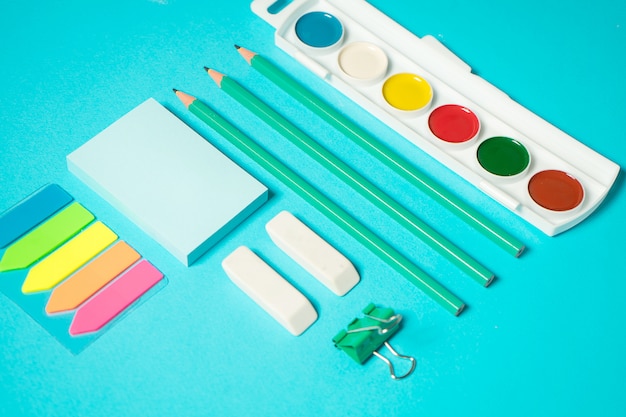 Back to school mock up. Flat lay composition with a watercolor, pencil, sticker, eraser. Isometric concept on blue background. Pop art. School supplies. overhead. Branding mock up stationery