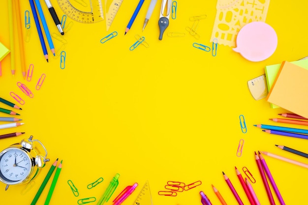 back to school or office styed scene with multicolored school supplies on yellow background