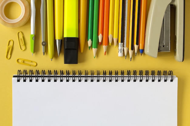 Back to school . Open empty mockup notebook and colored school stationery. Yellow paper background.