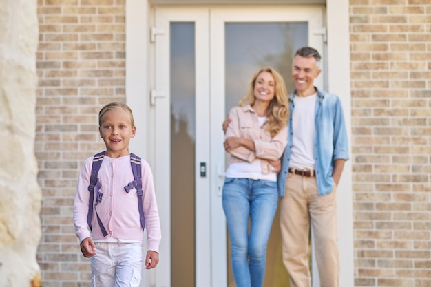 Back to school. Parents sending a girl to sschool in the morning