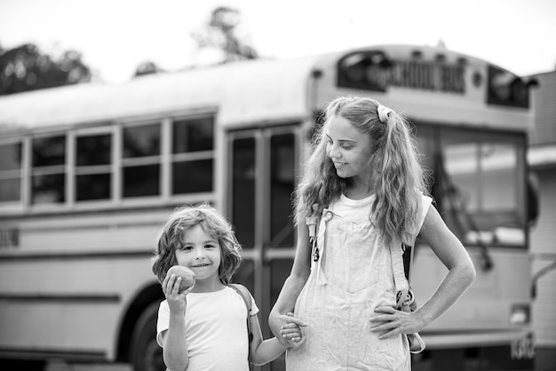 Back to school. Photo of two happy children looking out the windows of a yellow school bus. Plenty of space for text.