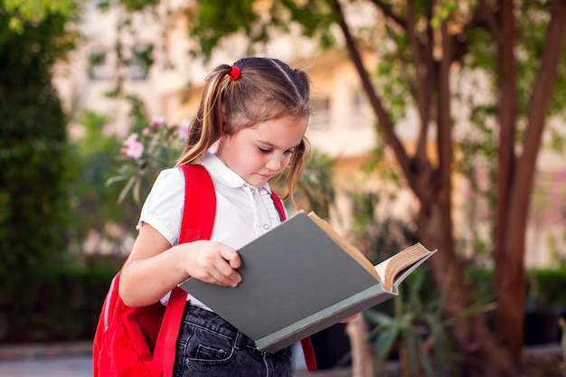 Back to school. Pupil reading book outdoor